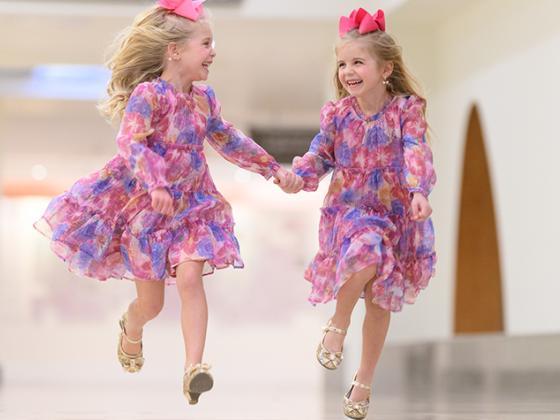 Twin girls skipping down a hallway